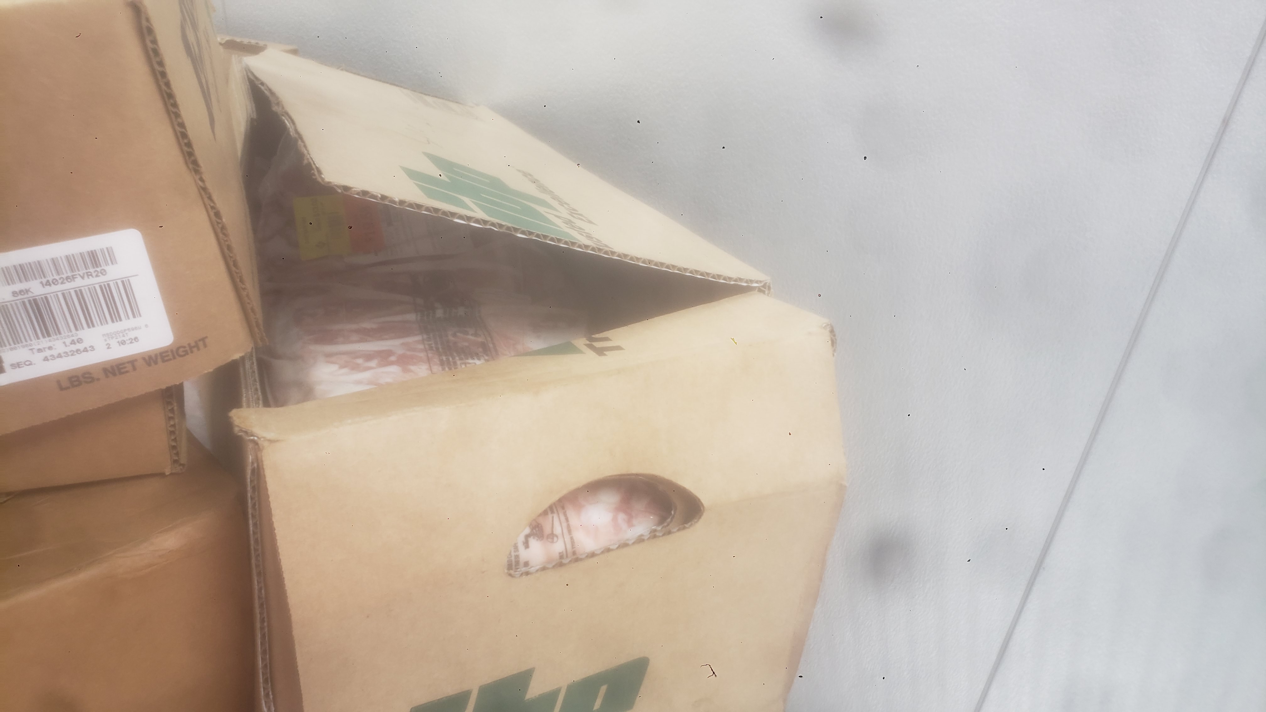 Cardboard boxes stacked on each other. One is open with a pack of baby back ribs.